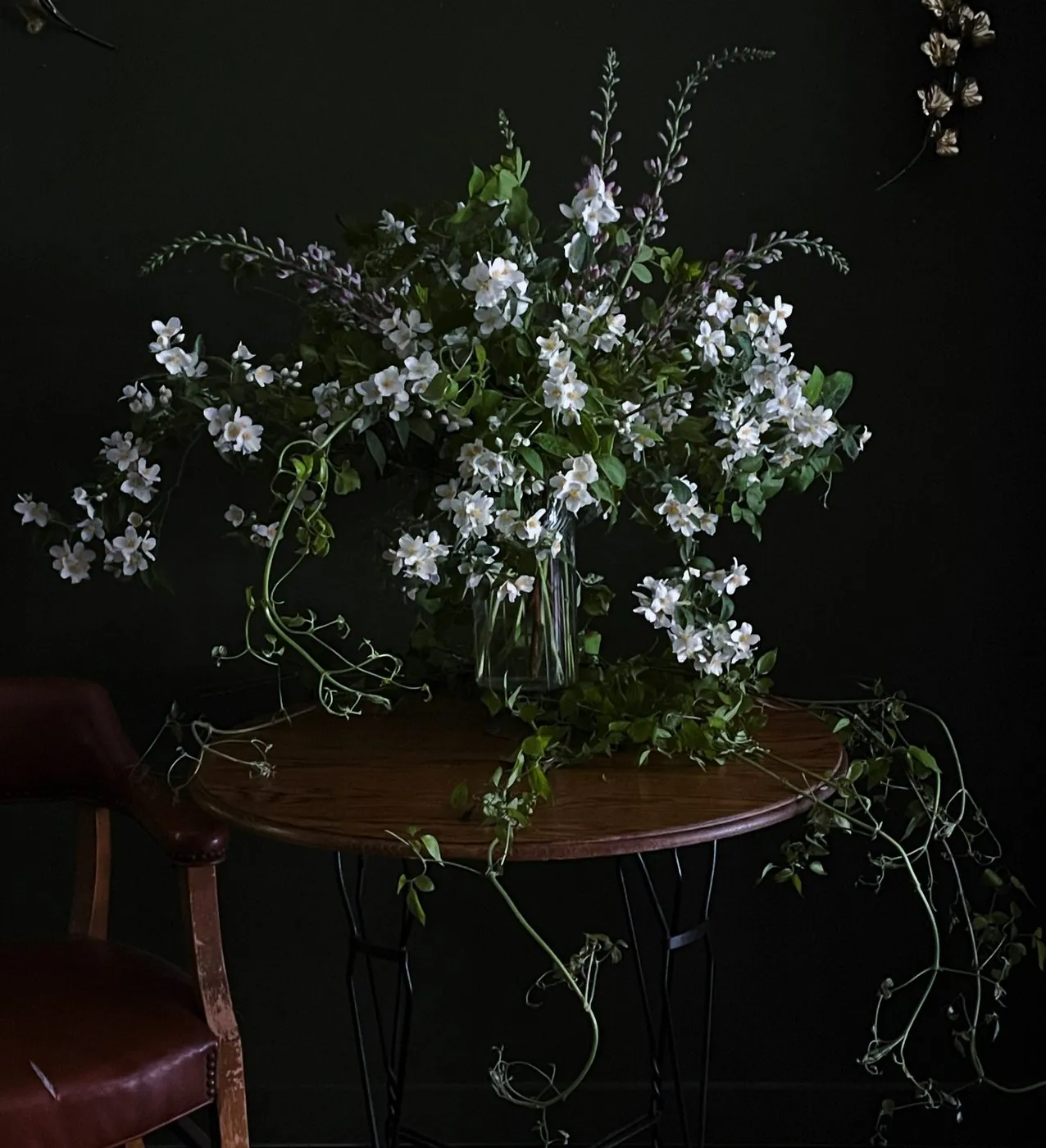 Mock orange and baptisia gathered in glass on a dark table